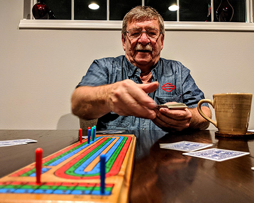 An older Wisconsin gentleman, Dennis Brunner, animatedly playing cribbage.